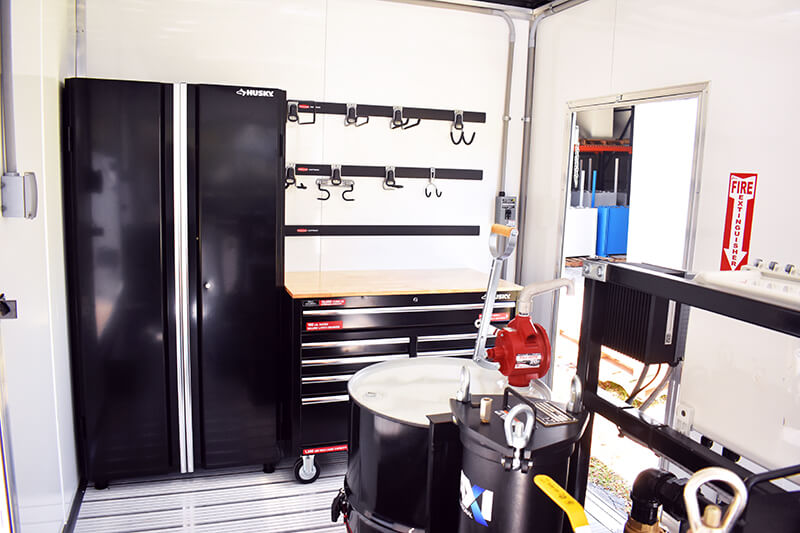 Interior of the fuel polishing trailer showing storage, workbench, fire extinguisher, waste oil drum, and more.